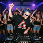 DJ with blue hair and sunglasses wearing DJ At Work oversized black t-shirt performing at nightclub