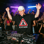 DJ wearing DJ At Work oversized t-shirt performing on Pioneer decks in front of cheering club crowd