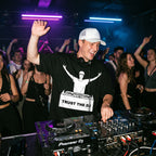 Male DJ wearing Trust The DJ Quote Oversized T-Shirt performing in club hand raised