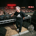 DJ in DJing Is An Art oversized black t-shirt performing on outdoor festival stage in front of large crowd