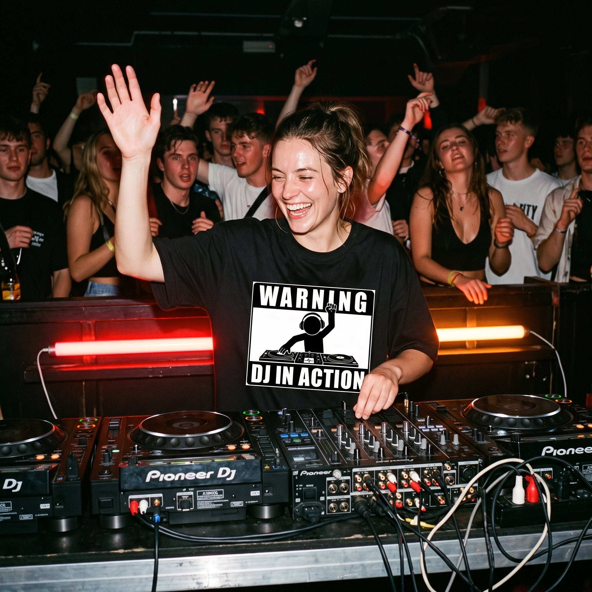 Female DJ wearing Warning DJ In Action Oversized T-Shirt performing in club hand raised