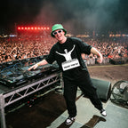 Male DJ wearing Trust The DJ Quote Oversized T-Shirt on festival stage massive crowd