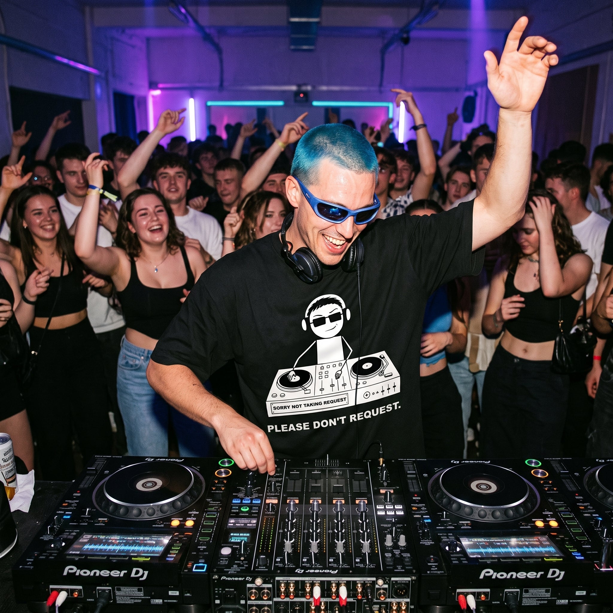 DJ with blue hair and sunglasses wearing Please Don't Request oversized black t-shirt performing at nightclub