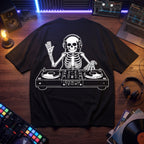 Black oversized t-shirt with skeleton DJ graphic mixing on turntables, flat lay on wooden desk with DJ controller and vinyl records