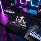Black oversized DJ t-shirt with skeleton DJ graphic laid flat under neon purple and blue studio lighting