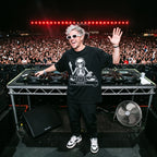 DJ in skeleton DJ graphic oversized black t-shirt performing on outdoor festival stage in front of large crowd