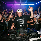 DJ wearing Support Your Local DJ black oversized t-shirt performing on Pioneer decks in front of cheering crowd