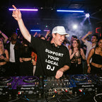 Male DJ in Support Your Local DJ oversized streetwear tee mixing tracks on DJ controller at nightclub