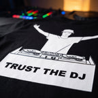 Close up print detail of Trust The DJ Quote Black Oversized T-Shirt DJ controller background