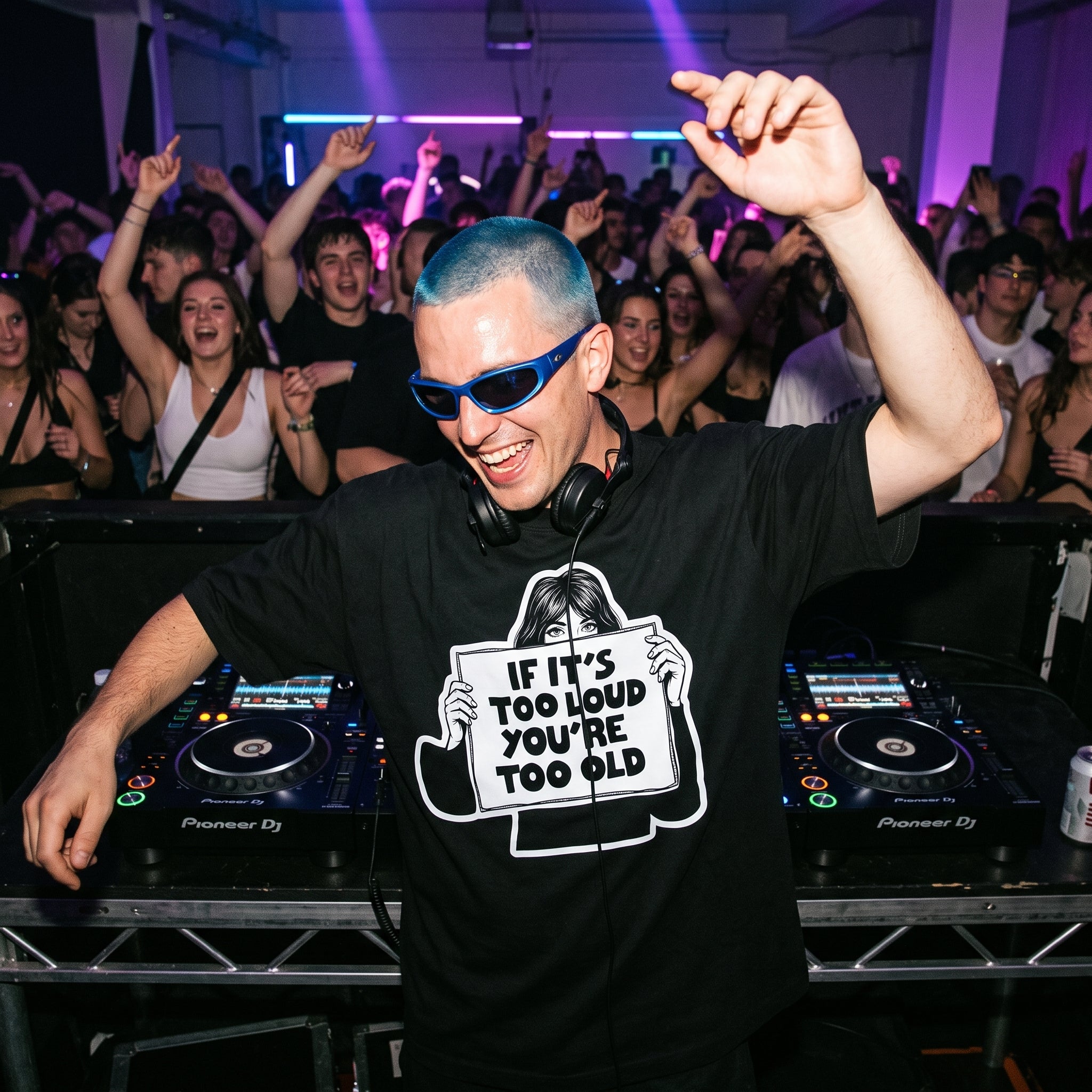 DJ with blue hair and sunglasses wearing If It's Too Loud You're Too Old oversized black t-shirt performing at nightclub