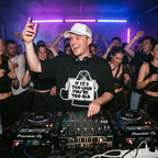 DJ wearing If It's Too Loud You're Too Old oversized t-shirt performing on Pioneer decks in front of cheering club crowd