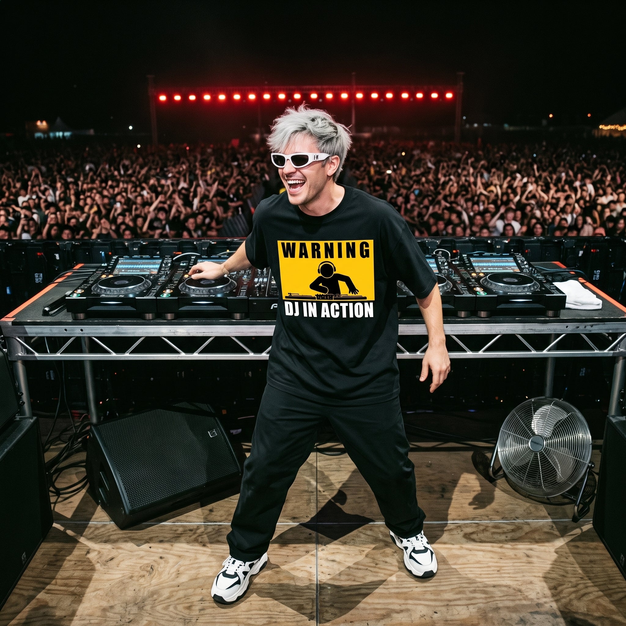 DJ in Warning DJ In Action oversized black t-shirt performing on outdoor festival stage in front of large crowd