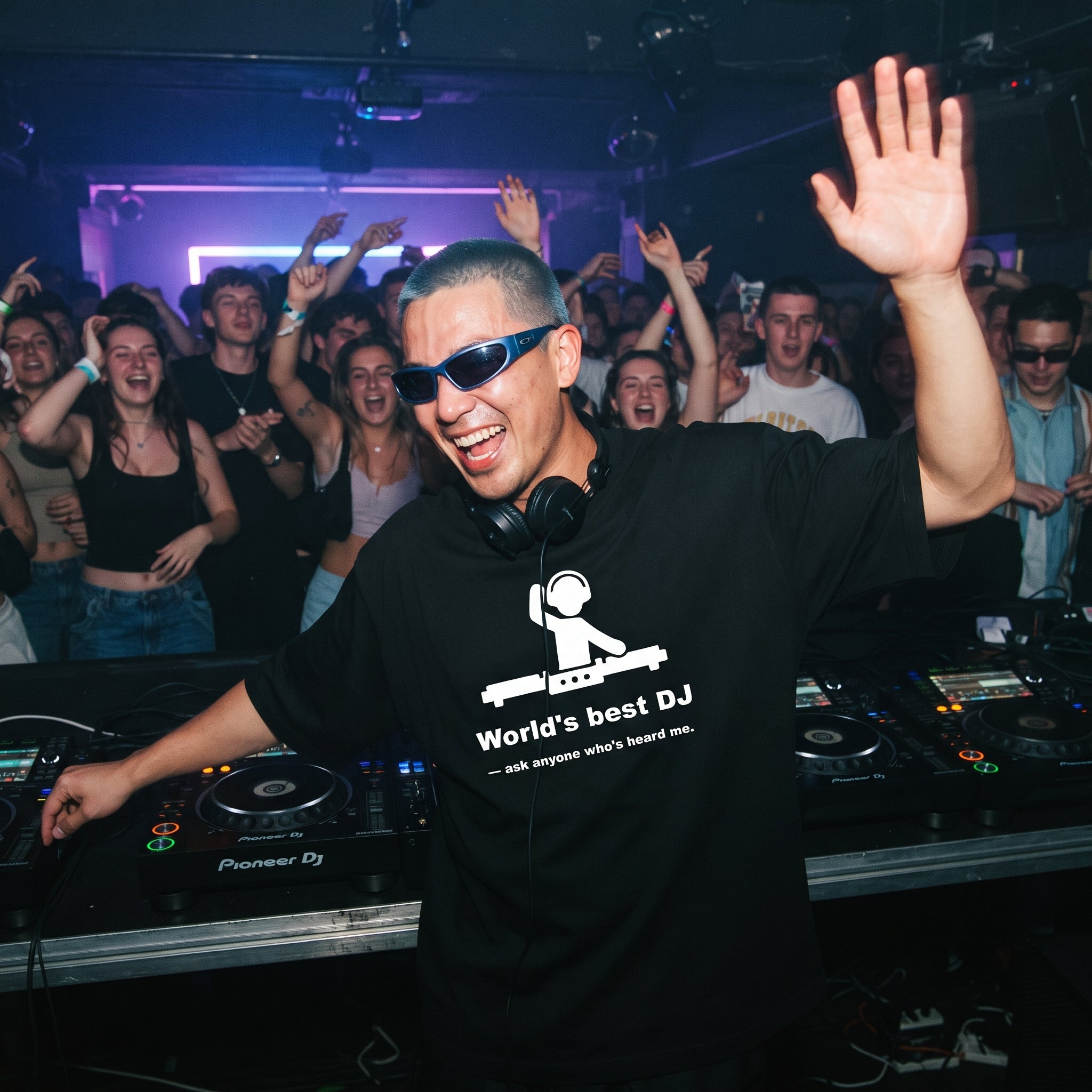 DJ with blue hair and sunglasses wearing World's Best DJ quote oversized black t-shirt performing at nightclub