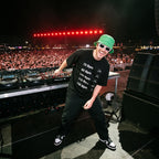 Male DJ wearing BPM Chart Oversized T-Shirt on festival stage with massive crowd