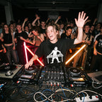 Female DJ wearing DJ Turntable Graphic Oversized T-Shirt performing in club hand raised crowd