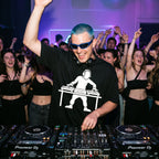 Male DJ in DJ Turntable Graphic Black Oversized T-Shirt packed club blue hair sunglasses crowd